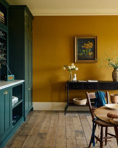 a dining room with yellow walls and wooden floors