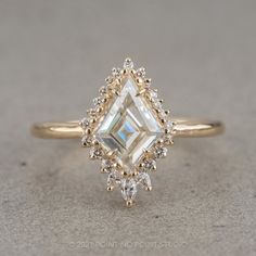 an engagement ring with a square cut diamond surrounded by smaller round and triangle shaped diamonds