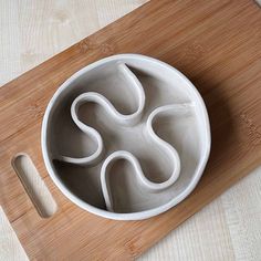 a wooden cutting board with a bowl and spoon on it