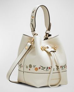 STRATHBERRY "Lana Osette" calf leather bucket bag with floral trim     Top handle     Detachable crossbody strap    Can be worn as a top handle or crossbody bag     Drawstring closure with metal bar accent     Lining: Polyester    Approx. 6.5"H x 5.5"W x 5.2"D    Item Weight (Lbs.): 0.8    Made in Spain Flowers And Animals, Scandinavian Folk Art, Spring Makeup, Trim Top, Leather Bucket Bag, Leather Bucket, Metal Bar, Bird Print, Printed Bags