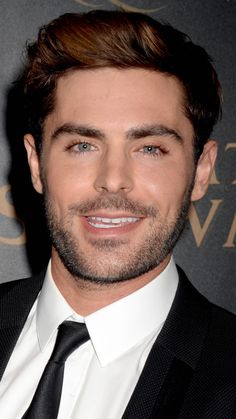 a close up of a person wearing a suit and tie with a smile on his face