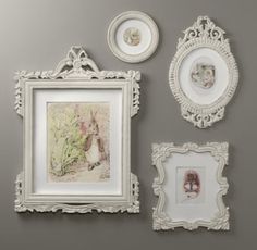 an assortment of framed pictures on a gray wall with white trimmings and ornate frames