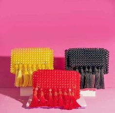 three different colored bags with tassels and fringes on the front, one in yellow, one in red