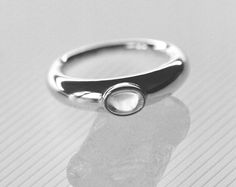 A punctuating 4x6mm oval quartz cabochon stone, bezel set on a graduated and full round solid band.The Glacé Ring I is part of our classic Glacé Collection, pairing solid, 100% recycled 14k gold or sterling silver with clear quartz; equal parts modern statement and a relic that could belong to any era. Exploring the limits of shape through our signature lens of timelessness and wearability, our Glacé collection includes both our permanent clear quartz styles and evolving capsules incorporating l Modern Moonstone Ring With Oval Bezel Setting, Oval Modern Moonstone Ring With Bezel Setting, Modern Oval Moonstone Ring With Bezel Setting, Classic Oval Cabochon Jewelry For Everyday, Timeless Oval Moonstone Ring With Polished Finish, Modern Domed Ring With Bezel Setting, Modern Jewelry With Bezel Set Oval Cabochon, Modern Moonstone Ring With Oval Cabochon, Modern Jewelry With Oval Cabochon Bezel Setting