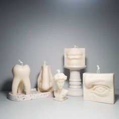 a group of candles sitting next to each other on top of a table in front of a gray background