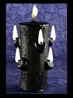 a black candle with white candles sticking out of it's sides and eyes on top