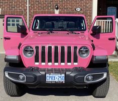 a bright pink jeep parked in front of a brick building with the license plate on it