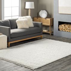 a living room with a gray couch and white rug