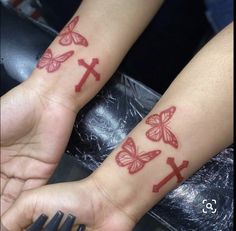 two people with matching tattoos on their arms and wrist, both have crosses painted on them