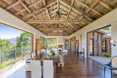 a large open floor plan with wooden ceiling and white dining room furniture, overlooking the mountains