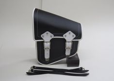 a black and white bag with two straps on the front, sitting on a white surface