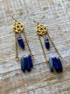 Handmade with gold tone chain and charms, and lazurite stones. Measures about 3.25 inches tall Gold Lapis Lazuli Pierced Jewelry, Gold Lapis Lazuli Jewelry, Mystical Wire Wrapped Dangle Jewelry, Celestial Metal Jewelry With Dangling Charms, Wire Wrapped Lapis Lazuli Dangle Earrings, Brass Dangling Charms Drop Earrings, Symbolic Brass Dangle Jewelry, Blue Brass Dangle Jewelry, Blue Brass Jewelry With Adjustable Chain