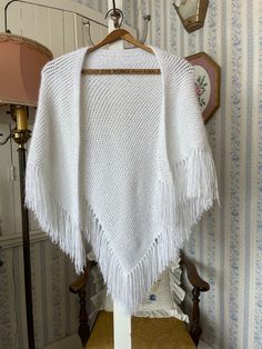 This lovely shawl was knit by hand from white yarn with longer strands of shiny silver/white fibres, giving the shawl a pretty sparkle! It is trimmed with a long fringe made of the same yarn. The measurements, taken with the shawl lying flat, are: width at widest point, 48 inches (not including fringe); length at longest point, 26 inches (not including fringe); fringe, 5 inches. In very good condition. White Fringe Shawl, White Bohemian Shawl With Fringe, Bohemian White Shawl With Fringe, White One-size Shawl Wrap, White Shawl Wrap, Long Beige Coat, Fringe Shawl, White Fringe, Beige Coat