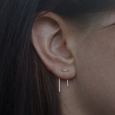 a close up of a person's ear with two small bar earrings on it