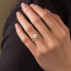 a woman's hand wearing a gold ring with a diamond on the middle finger