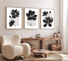 three black and white flowers are hanging on the wall above a chair in a living room