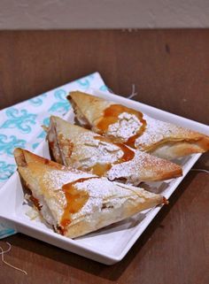 three pastries are sitting on a plate with powdered sugar and syrup drizzled over them