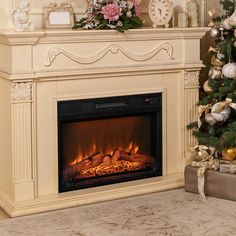 a decorated christmas tree in front of a fireplace with an electric fire and clock on the mantle