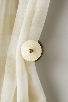 a white curtain with a gold button on it