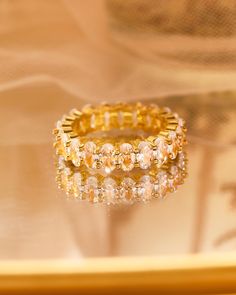 a stack of gold rings sitting on top of a glass table next to a mirror