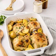 chicken and potatoes in a white casserole dish with parsley on the side