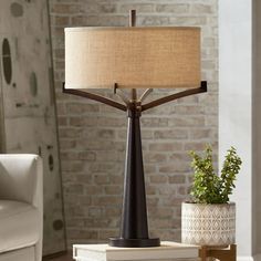 a table lamp sitting on top of a pile of books next to a white couch