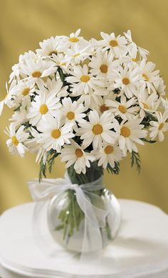 a vase filled with white daisies on top of a table