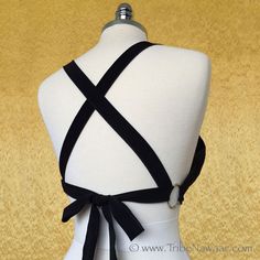 a white mannequin with black ribbon on it's back and neckline