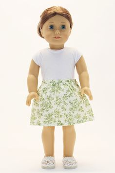 the doll is wearing a white shirt and green skirt