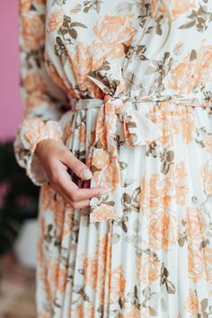 The Oakley Midi dress in a cream base with a peach and brown rose floral design is both stylish and functional. With a high neck, zipper in the back, and long sleeves with elastic cuffs, this dress is comfortable and easy to wear. The elastic waist with a tie creates a flattering silhouette, while the pleated bottom adds a touch of elegance. Model is wearing a small and is 5'8". Plus model is wearing a 2X and is 5'11". Size Chart Length Bust Waist S 47" 34" 32" M 47" 37" 34" L 47.5" 40" 36" XL 47.5" 44" 38" XXL 48" 48" 41" XXXL 48.5" 52" 44" *Measurements are approximate and are measured while hanging* Fabric and Care 100% Polyester Hand wash cold. Do not bleach. Lay flat to dry. Low iron if needed or dry clean. Fall Cream Midi Dress With Floral Print, Flowy Cream Floral Print Midi Dress, Long Sleeve Cream Floral Midi Dress, Peach Floral Print Long Sleeve Dresses, Peach Long Sleeve Floral Print Dress, Cream A-line Midi Dress With Floral Print, Peach Floral Print V-neck Midi Dress, Teen Dress, Tiered Dresses