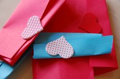 an origami heart is on top of some folded up pieces of red paper