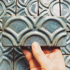 a hand is holding something in front of some tiles