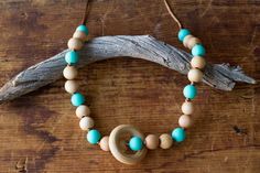 a wooden beaded necklace on a piece of driftwood with turquoise and white beads