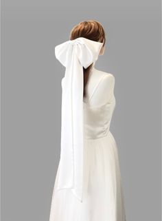 the back of a woman's white dress with a bow on her head and neck