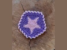 a purple and white crocheted brooch sitting on top of a tree stump