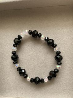 Black and clear faceted glass round beaded bracelet. This bracelet is made with an elastic string. Adjustable Faceted Crystal Bracelet With Round Beads, Adjustable Glass Crystal Bracelet With Faceted Beads, Glass Crystal Bracelet With Faceted Round Beads, Black Faceted Beads Crystal Bracelet For Party, Black Crystal Bracelet With Faceted Beads For Party, Clear Crystal Bracelet With Round Faceted Beads, Party Faceted Beaded Bracelets With Round Beads, Faceted Beaded Bracelets For Party With Round Beads, Crystal Stretch Bracelet With Faceted Beads