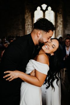 a bride and groom hugging each other in front of a group of people at a wedding