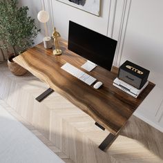 a wooden desk with a computer on it and a plant in the corner next to it