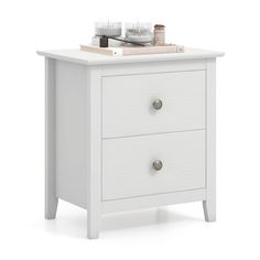 a white night stand with two drawers and candles on top of the drawer, against a white background