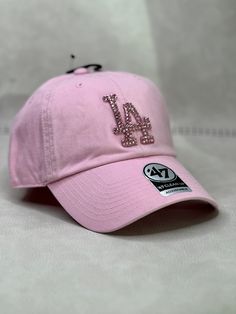 This is a light pink LA Dodgers 47 clean up women's adjustable hat that is hand embellished with matching pink Swarovski style crystals on the front logo. This hat features over 150+ Swarovski style crystals. - 100% Cotton - Matching fabric strap & buckle - One Size Fits All - Raised Embroidered Logo - 150+ Swarovski style pink crystals individually placed by hand - Ready to ship in 1 week from San Diego, CA Cheap Pink Hats With Embroidered Logo, Trendy Rhinestone Adjustable Baseball Cap, Trendy Snapback Baseball Cap With Rhinestones, Trendy Rhinestone Snapback Baseball Cap, Adjustable Rhinestone Baseball Cap With Curved Brim, Trendy Rhinestone Hats For Spring, Casual Rhinestone Cap, Casual Cap With Rhinestones, Adjustable Baseball Cap With Bling