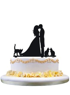 a wedding cake topper with a silhouette of a bride and groom kissing in front of two cats