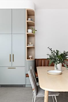 a dining room table with two chairs and a plant in the center on top of it