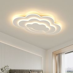 a bed room with a neatly made bed and a ceiling light that has clouds on it