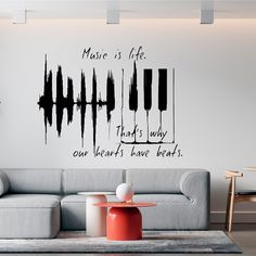 a living room with a couch, coffee table and wall decal that says music is life