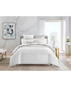 a bed with white sheets and pillows in a room next to a painting on the wall