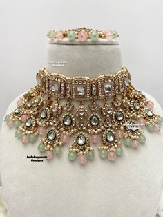 the necklace is adorned with pink and green stones, pearls, and other jewelry items