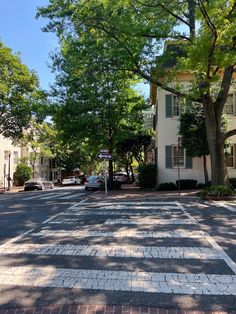 an empty street with cars parked on both sides and trees lining the sidewalks in front