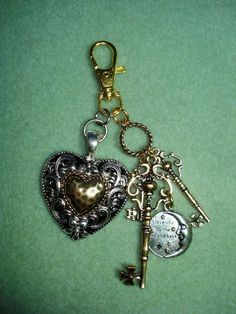 two heart shaped keychains with keys attached to each other on a green surface