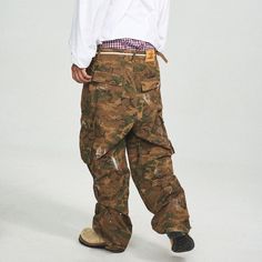 The Ink-Splashed Camo Cargo Pants in green offer a perfect fusion of vintage style and modern craftsmanship. Featuring a bold camo pattern with striking white ink-splatter detailing, these pants bring a unique twist to the classic cargo look. The distressed, ripped accents add a rugged edge, while the multi-pocket design ensures functionality. With adjustable waistband buckles and a leather logo patch on the back, these pants are crafted from premium 100% cotton and offer a slightly oversized fi Casual Paint Splatter Streetwear Bottoms, Urban Cotton Bottoms With Paint Splatter, Urban Style Cotton Bottoms With Paint Splatter, Urban Style Paint Splatter Cotton Bottoms, Baggy Military Bottoms For Streetwear, Military Style Cargo Pants, Military Cargo Pants For Streetwear, Military Style Baggy Pants For Streetwear, Urban Camouflage Bottoms For Fall