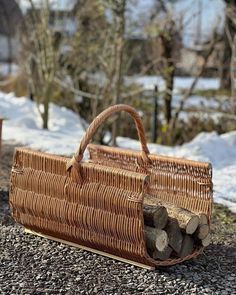 a brown wicker bag sitting on top of a pile of logs in the snow